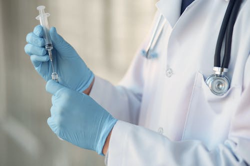 doctor holding syringe in gloved hands